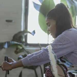 Young ethnic woman setting up smartphone before filming blog